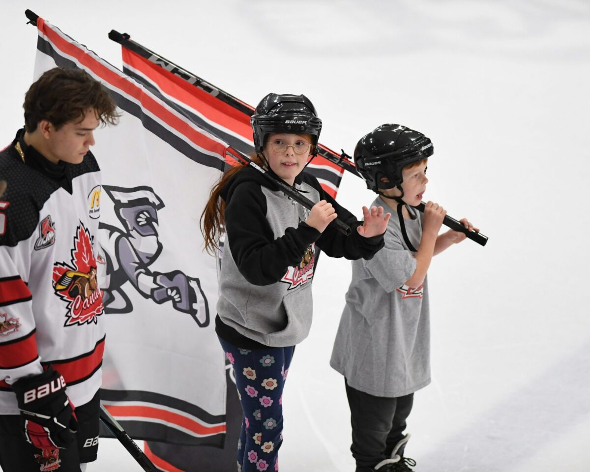 Young minor hockey players carry flags onto the ice at the Gale Centre